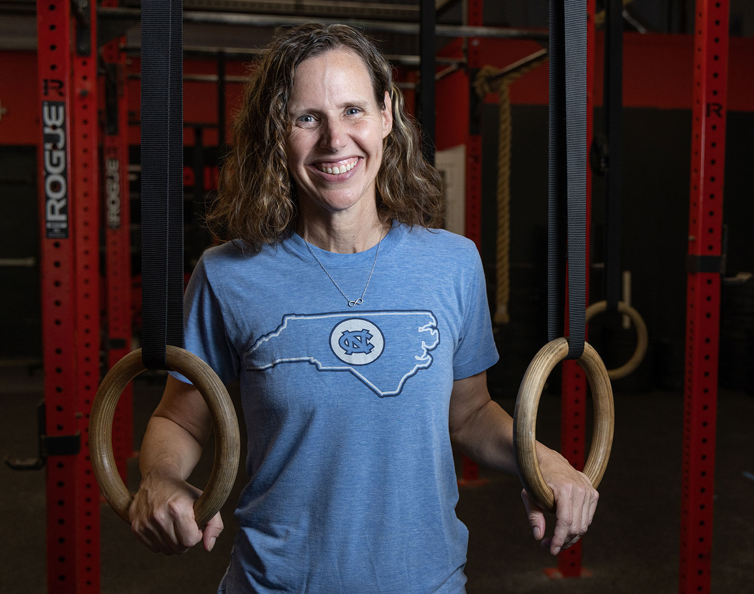 Kara Hume poses with her hands in rings at a gym