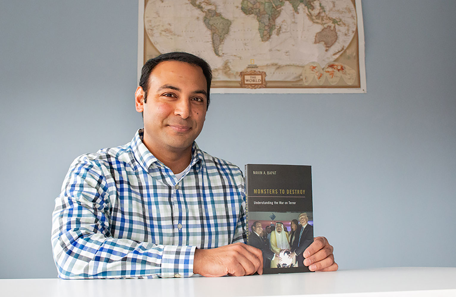 Navin Banat sits behind a table holding a book