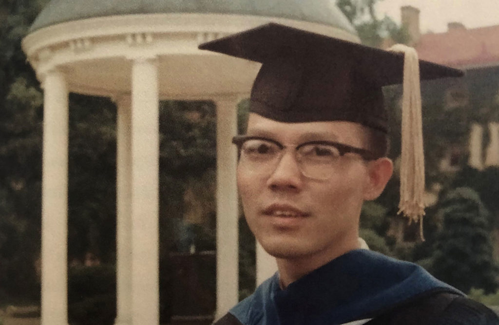 Cliff Huang poses by the Old Well to commemorate the earning of his doctorate from UNC-Chapel Hill in 1968.