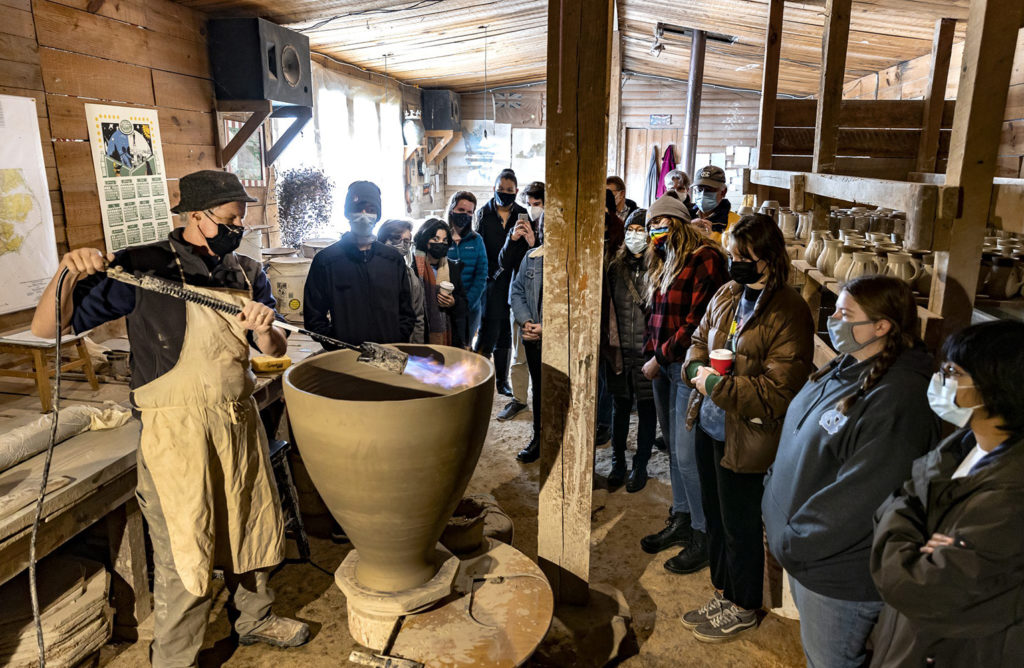 Mark Hewitt demonstrates using a flame to dry and harden pottery to the class