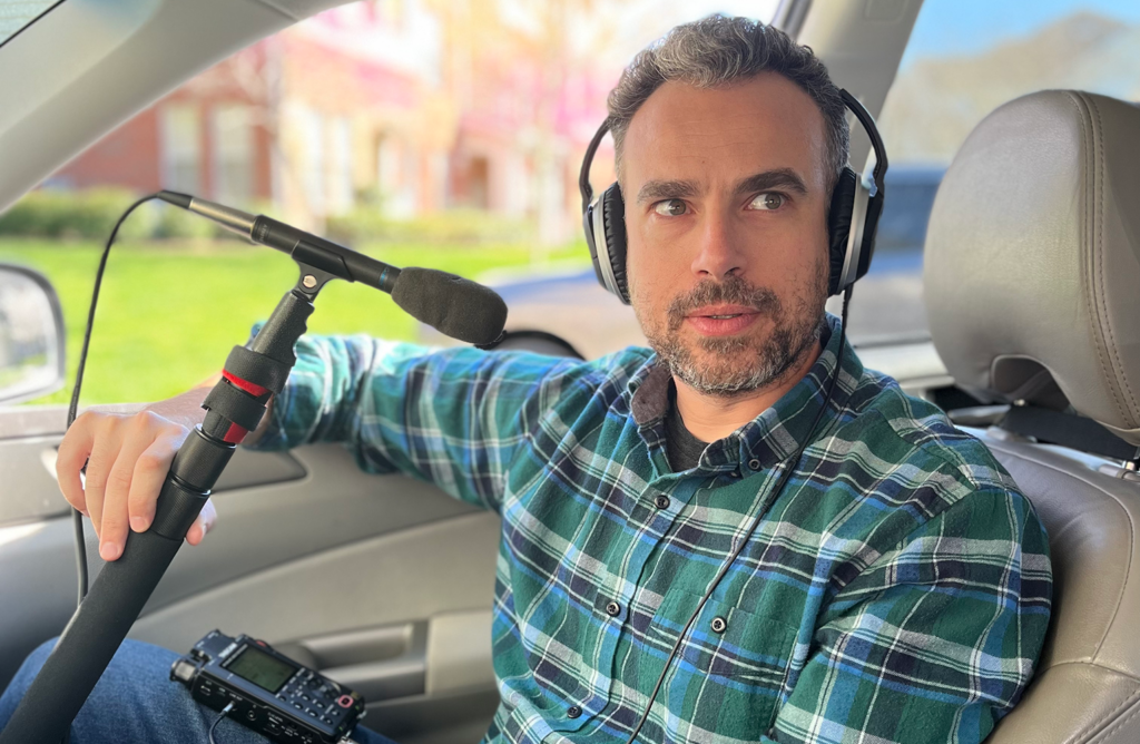 Isaac Klein sits with recording equipment in his car