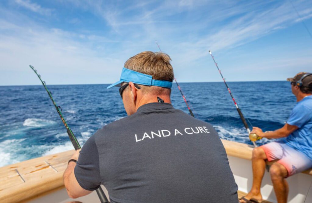 A fisher wears a t-shirt that says "Land A Cure".