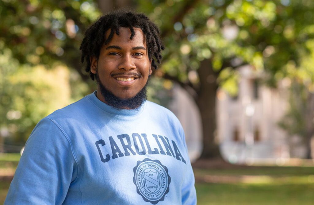 Daniel Garcia stands in front of a tree while wearing a Carolina sweatshirt