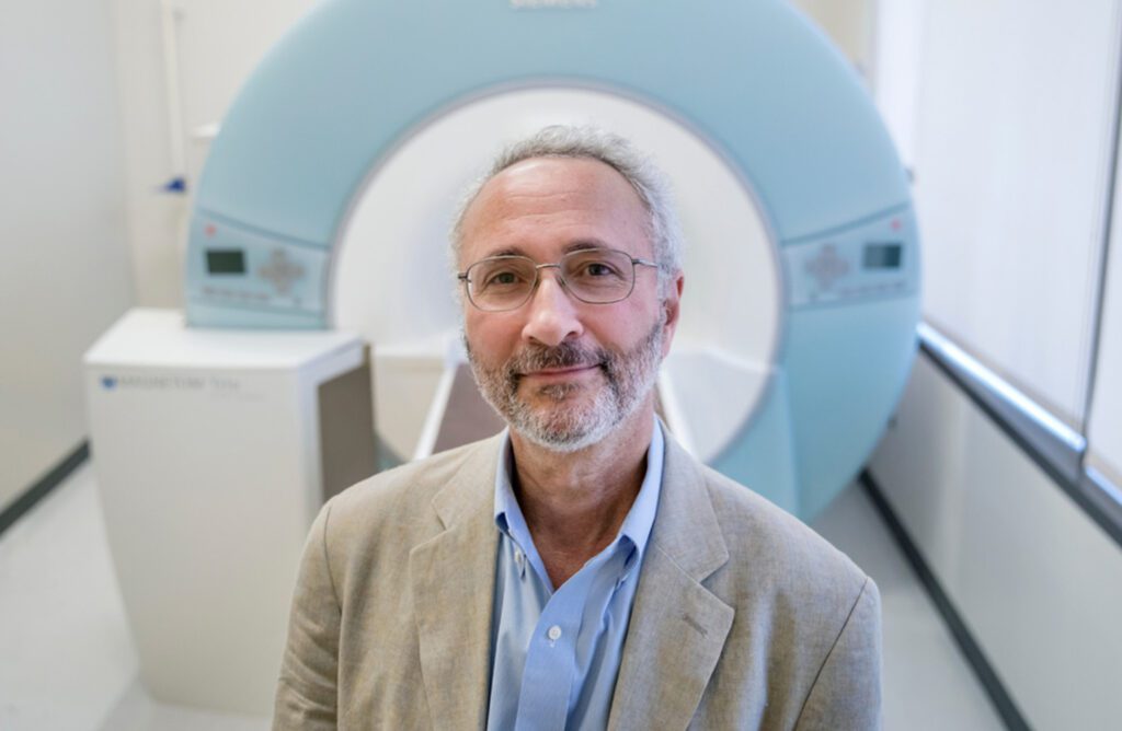 Dr. Joe Piven stands in front of a MRI machine