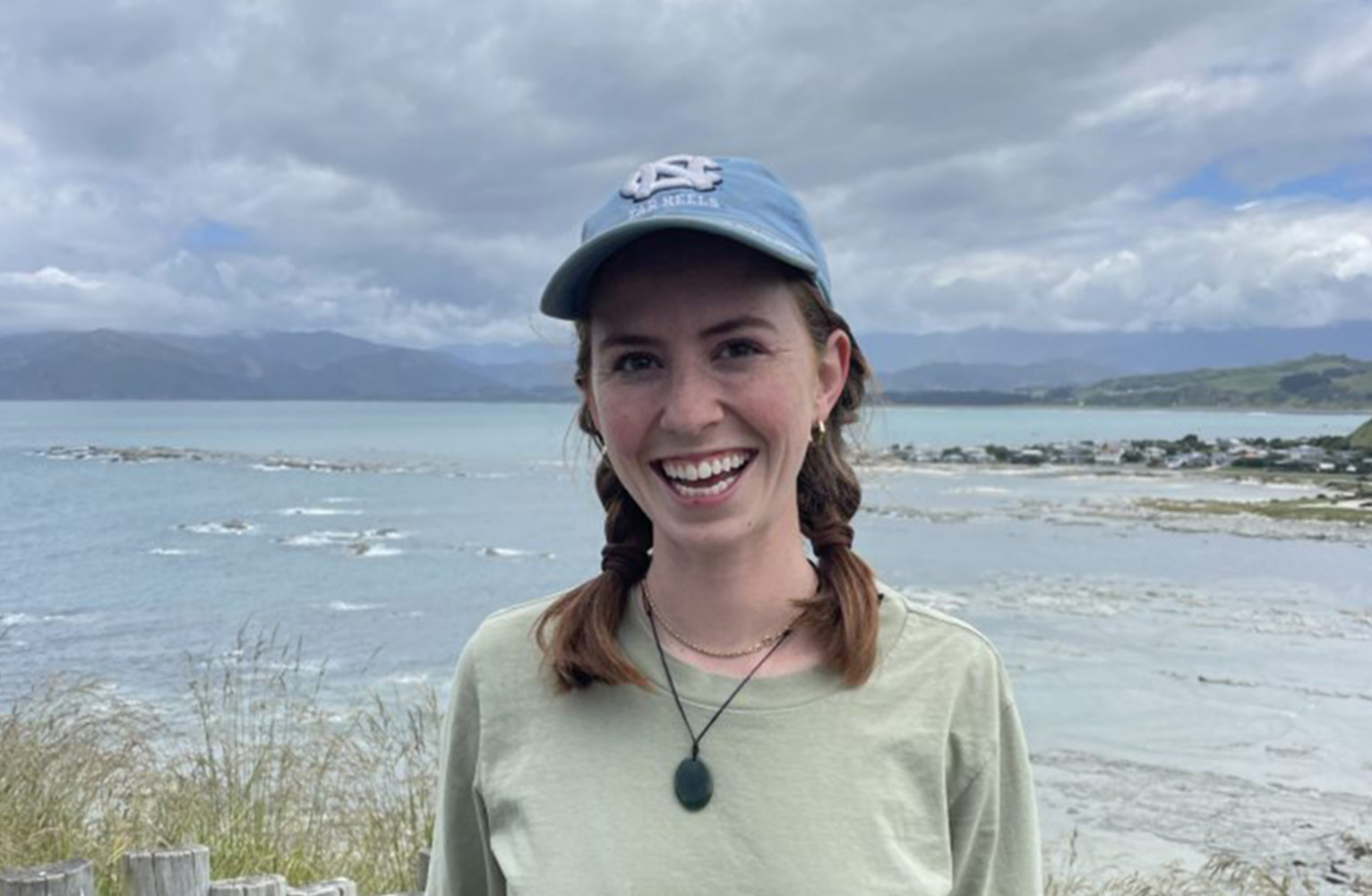 Charlotte Dorn stands on the coast wearing a UNC hat