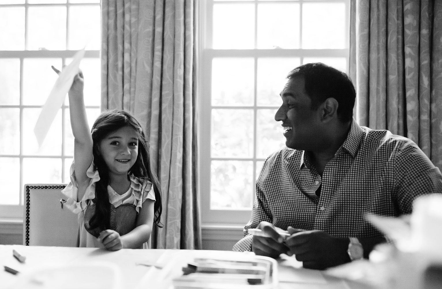 Black and white photo of Ana holding a piece of paper above her head as her father Nigaraj looks at her fondly